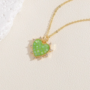 Gros plan du pendentif coeur à damier vert avec cristaux sertis sur une chaîne dorée