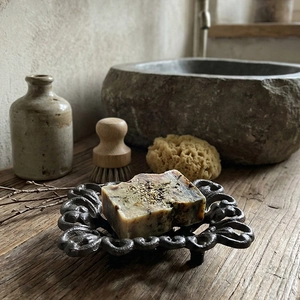 Vintage iron soap dish with floral hollow design and handmade soap on rustic wood