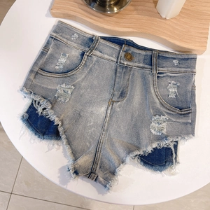 Dettaglio ravvicinato di pantaloncini in denim azzurro con bordi sfrangiati e toppa interna