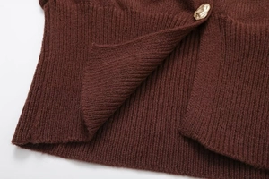 Detailed close-up of dark brown knit cardigan texture with irregular gold metal button