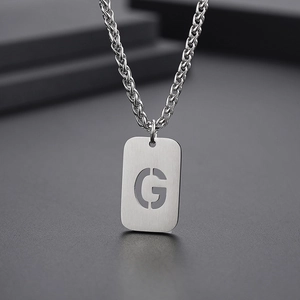 Vue macro d'un collier avec pendentif rectangulaire argenté et lettre G ajourée