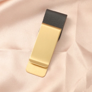 Dettaglio di clip per penna vintage in metallo oro opaco con trama in pelle nera