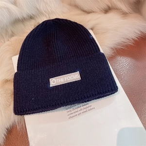 Detail shot of navy blue ribbed knit beanie with THE FOCUS embroidered patch