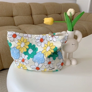 Close-up of floral cotton pouch with silver metal zipper and brand woven label detail