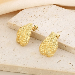 Macro detail of golden heart earrings with hammered honeycomb texture on stone