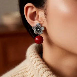 Vintage silver flower earrings with elegant red pearl drop on a woman wearing knitwear