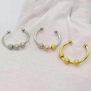 Close-up of rotatable frosted beads on stainless steel rings in silver and gold finishes