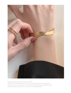 Dettaglio del bracciale a polsino in oro opaco e anelli a doppio strato con strass al polso
