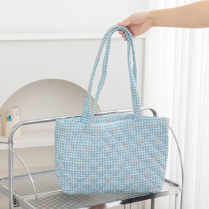 Detail of blue plaid quilted tote bag featuring pink bow embroidery and soft cotton texture