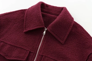 Détail d'une veste en tweed bordeaux avec fermeture éclair métallique et col texturé