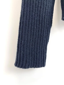 Detailed macro view of the ribbed knit texture and elastic cuff on this navy blue sweater