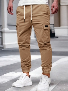 Detail of khaki cargo pants featuring large side pockets and elastic ankle cuffs
