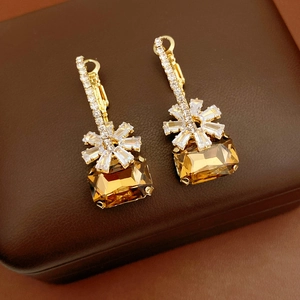 Dettaglio di orecchini placcati oro 18k con fiore di zircone e pietra ambra rettangolare