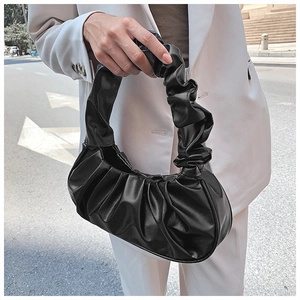 Lifestyle shot of a black pleated cloud bag held by a model in a white blazer jacket