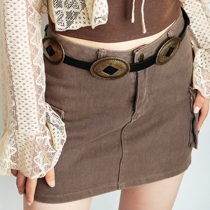 Detail of a brown corduroy A-line skirt with large pockets and vintage bronze belt buckles