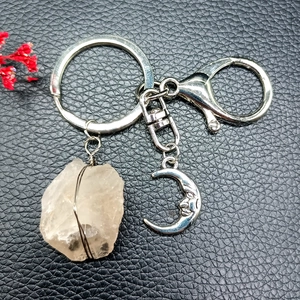 Detail of silver crescent moon keychain with wire-wrapped raw natural crystal on leather