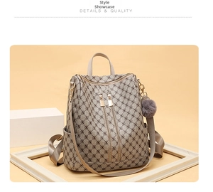 Close-up of vintage monogram backpack featuring dual front zippers and a fluffy pom pom charm