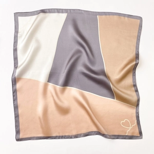 Close-up of geometric striped silk square scarf showing soft texture and beige gray tones