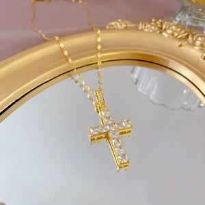 Close-up of golden titanium necklace featuring a luxury cross pendant set with white zircons