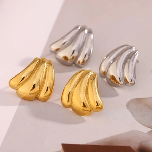 Detailed view of pumpkin style stud earrings in polished gold and silver finishes