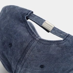 Close-up of washed navy cotton baseball cap with adjustable silver metal buckle detail