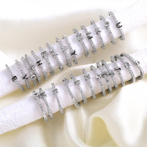 Sparkling silver initial ear cuffs with crystal pavé on white satin display stands