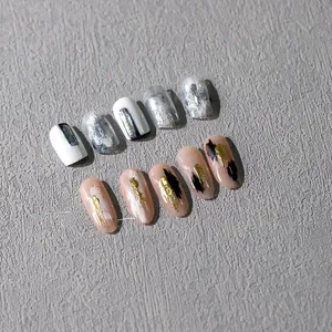 Detail of silver foil ink texture and gold leaf nail art stickers in almond shape