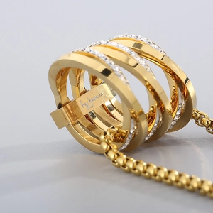 Close-up of golden multi-layer ring pendant with inset clear stones on box chain
