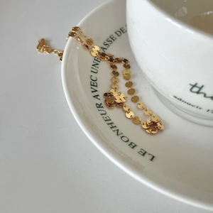 Detail of 925 sterling silver gold-plated disc choker on elegant white ceramic tray
