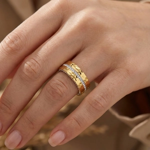 Detail of wide gold ring with hammered texture and pave-set cubic zirconia on finger