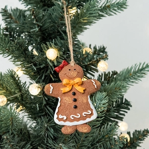 Gingerbread woman Christmas tree ornament with red bow and cozy warm festive background