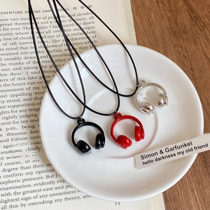 Colliers pendentifs casque créatifs en rouge, noir et argent sur une assiette blanche