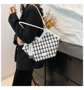 Detail of checkered tote bag with woven texture and leather straps on female model
