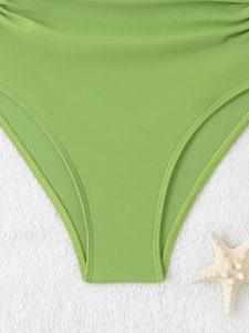 Close-up of grass green swimsuit fabric with precise double-stitching on a beach towel