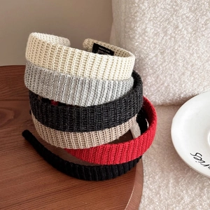 Set of five elegant knitted headbands in assorted colors displayed on a wooden tray