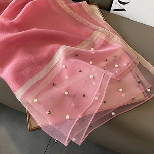 Detail of pink silk-like scarf with white pearl embellishments and gold metallic trim