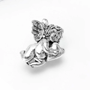 Close-up of vintage silver angel bead with wings resting on a textured metal heart
