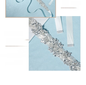 Detail of luxury bridal belt with hand-sewn rhinestones in floral patterns on white ribbon