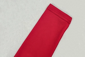 Detail of red ruched dress showing high-quality double stitching and elastic knit fabric