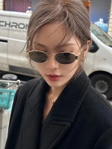 Outdoor street style shot of oval metal sunglasses worn with a black coat