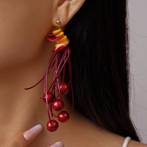 Detail of bohemian red and yellow tiered petals with deep wine red beaded tassels earring