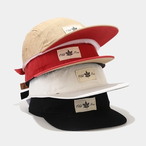 Close-up of assorted 5-panel flat bill caps with vintage woven labels and cotton texture