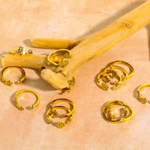 Golden zodiac month flower rings set with colorful zircons on a rustic wood branch