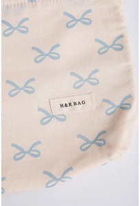 Close-up of cream cotton makeup bag showing blue bow patterns and fabric texture detail