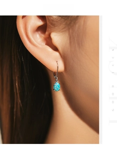 Close-up of elegant s925 sterling silver drop earring with oval blue opal on a model