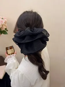 Close-up of a large black layered mesh scrunchie styled on a low ponytail ponytail