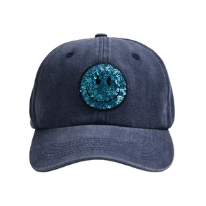Close-up of a blue sequined smiley face patch on a washed denim baseball cap detail