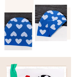 Dettaglio del berretto in maglia blu con motivo a cuore bianco e trama in tessuto morbido