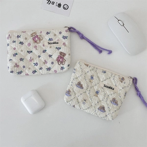 Quilted floral pouch size comparison with earphones and mouse on a clean background