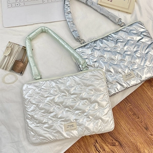 Quilted bow pattern tablet sleeve in white and silver with plush handles on bed